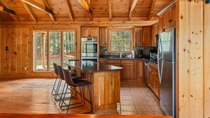 Een houten chalet van binnen met een keuken, een bar en grote ramen.