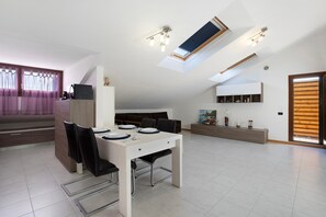 Un intérieur moderne comprenant un coin repas, un canapé, un espace cuisine et une lucarne.