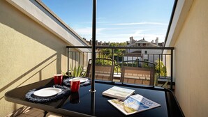 Un balcon avec une table, une tasse rouge, une assiette blanche et un magazine.