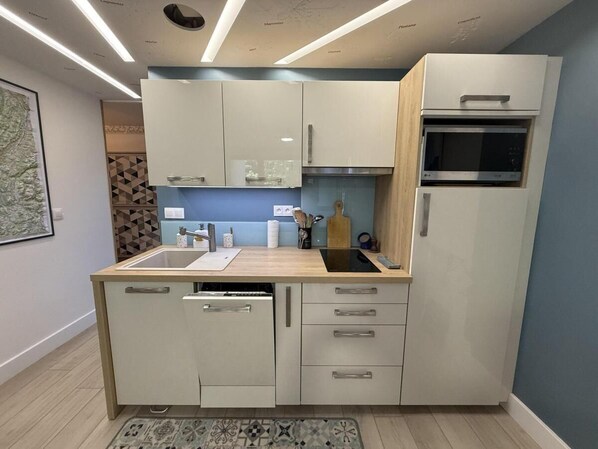 A compact kitchen with a dishwasher, a microwave, and a sink.