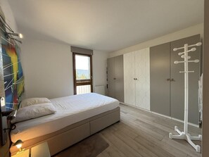 Quarto com cama, guarda-roupa e cabideiro.