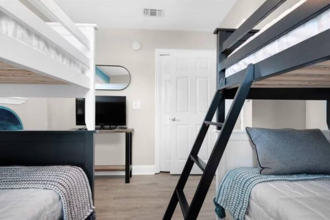 A bunk bed room with a desk and a TV.