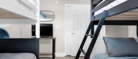 A bunk bed room with a desk and a TV.
