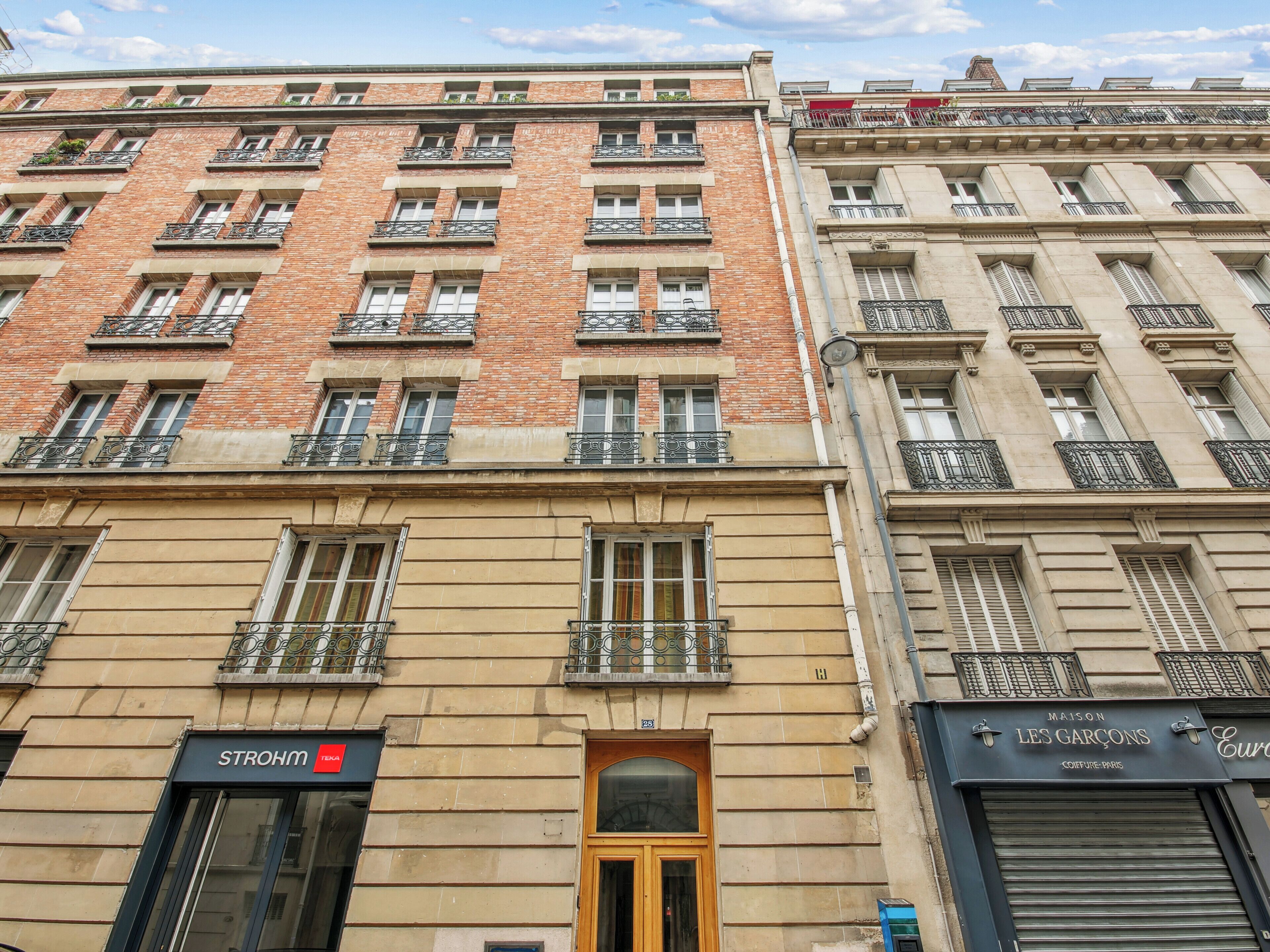 A multi-story building with a brick facade, multiple balconies, and storefronts.