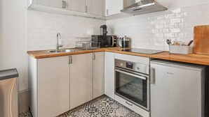A compact kitchen with white cabinets, a stainless steel sink, a microwave, a coffee maker, and a refrigerator. - Champs de Mars - Ecole Militaire 1bdr by B'Your Home (Paris)