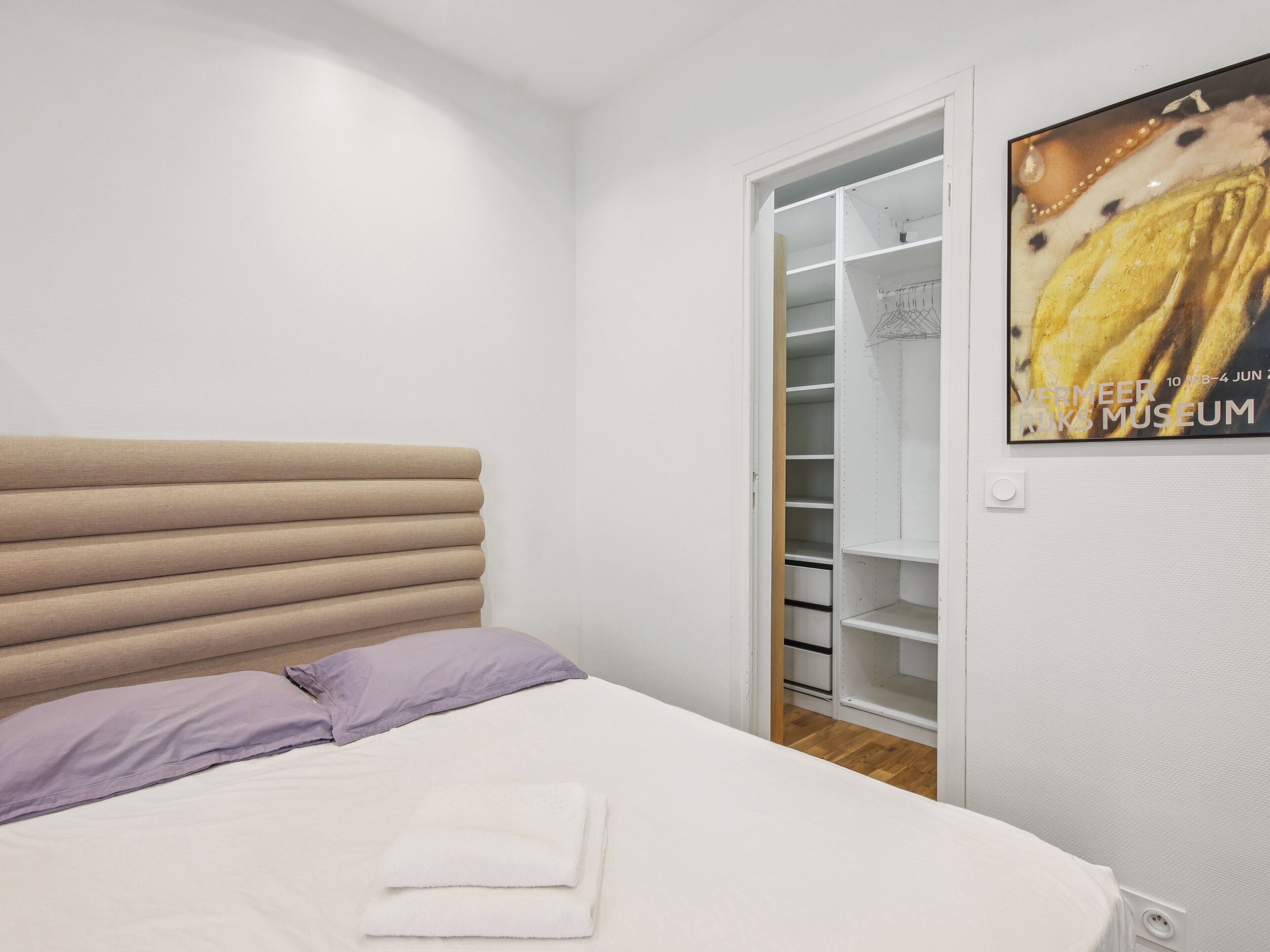 A bedroom with a bed, a closet, and a poster on the wall.