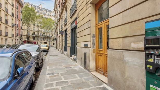 A narrow street lined with parked cars and historic buildings with stone facades and balconies. - Champs de Mars - Ecole Militaire 1bdr by B'Your Home (Paris)