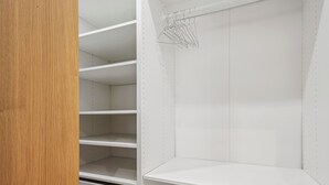 A closet with multiple shelves and hanging space, featuring metal hooks for hanging clothes. - Champs de Mars - Ecole Militaire 1bdr by B'Your Home (Paris)