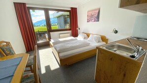 A hotel room with a bed, a desk, a sink, and a view of the outdoors. - Franglhof Hohe Salve (Kirchberg in Tirol)