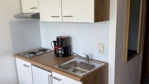 A compact kitchen with white cabinets, a wooden countertop, a coffee maker, and a sink. - Franglhof Hohe Salve (Kirchberg in Tirol)