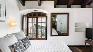 Un dormitorio con cama, televisor, ventana y lámpara.