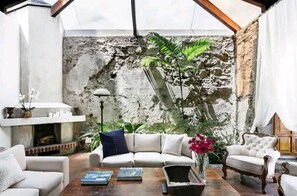 A living room with a stone wall, a white sofa, a wooden coffee table, and a potted plant.
