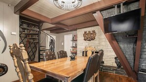 A dining area with a wooden table and leather chairs, a fireplace, and a decorative wall piece.