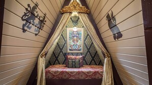 A cozy attic bedroom with a sloped ceiling, a bed with patterned bedding, and decorative wall art.