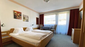 A hotel room with two single beds, a desk, a chair, and a TV. - Franglhof Fleckalm in Kirchberg (Kirchberg in Tirol)