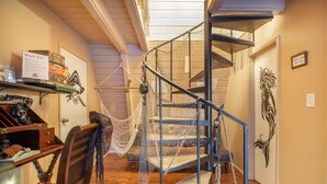 A spiral staircase with a rope barrier, a desk with a skull decoration, and a wall with a decorative emblem. - Pirate 2-story Villa Near Beach (Ocean Shores)