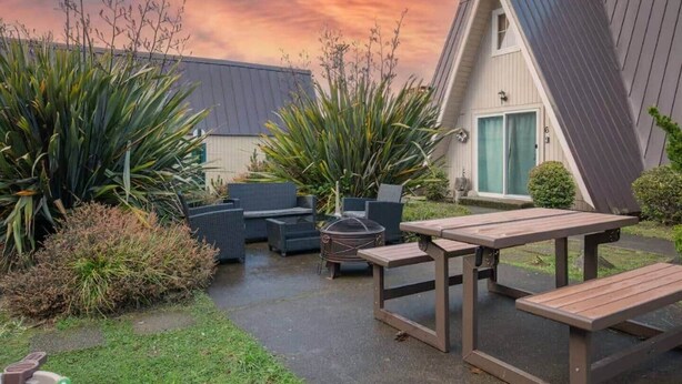 A house with a sloped roof, a patio with outdoor furniture, and a garden with various plants. - Pirate 2-story Villa Near Beach (Ocean Shores)