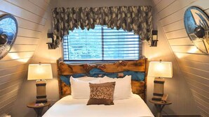 Un dormitorio con una cama grande, dos lámparas de noche, una ventana con persianas y un cabecero decorativo.