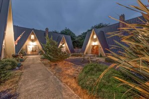 Eine Reihe von A-Chalets mit einem Kiesweg, der zum Eingang führt, umgeben von viel Grün.