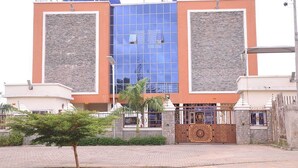 A modern building with a central glass facade, flanked by two symmetrical structures with stone cladding. - TILT APARTMENT (Bwari)