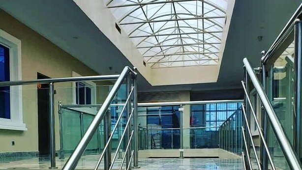 A modern interior with a glass staircase and a skylight. - TILT APARTMENT (Bwari)