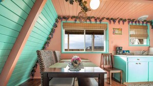 A cozy dining area with a table, chairs, and a window overlooking a cityscape. - Hawaiian 2-story Beach Villa (Ocean Shores)