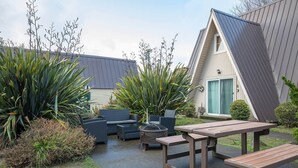 Un patio con mobiliario exterior, una chimenea y vistas a un edificio con tejado inclinado.