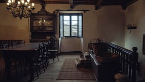 A traditional dining room with a wooden table and chairs, a chandelier, and a window with a view. - A Casa da Memoria - House-museum to live the experience of going back 100 years. (Aldea de Xullán)