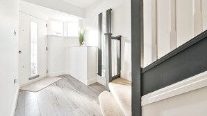 Een modern interieur met een trap, een deur met ruitpaneel, en een lichtgekleurde vloer.