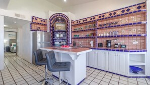 A compact kitchen with a central island, two bar stools, and a microwave. - Las Gaviotas 436 Mid-century Ocean View Apartment (Puerto Peñasco)