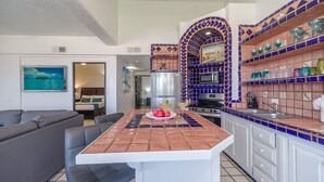 A compact kitchen with a tiled island, a refrigerator, a microwave, and a sink. - Las Gaviotas 436 Mid-century Ocean View Apartment (Puerto Peñasco)