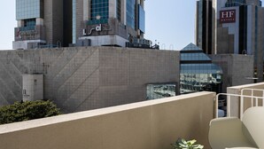 A modern hotel with a unique architectural design, featuring a prominent glass facade and a rooftop terrace with white chairs and a small round table. - Bom Sucesso Executive Prime Studios (Oporto)