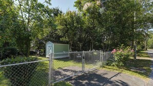 Un espace clos, avec un abri de jardin vert, une clôture en métal et un panneau indiquant qu'il est interdit d'y pénétrer.