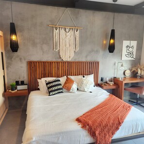 A modern bedroom with a wooden headboard, a macrame wall hanging, and a bed with patterned pillows.