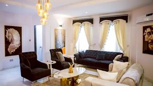 A modern living room with a black sofa, two armchairs, a coffee table, and a chandelier. - TAJ SUITES  (Ado Ekiti)