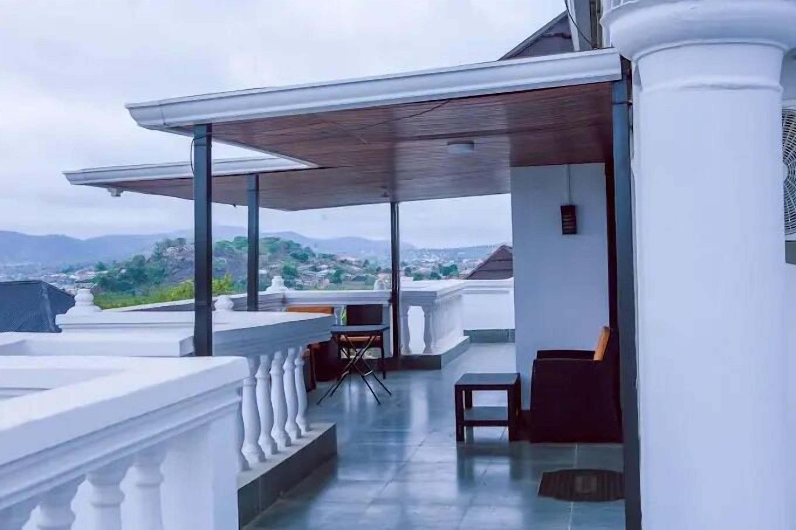 A rooftop terrace with a covered seating area, a small table, and a chair.