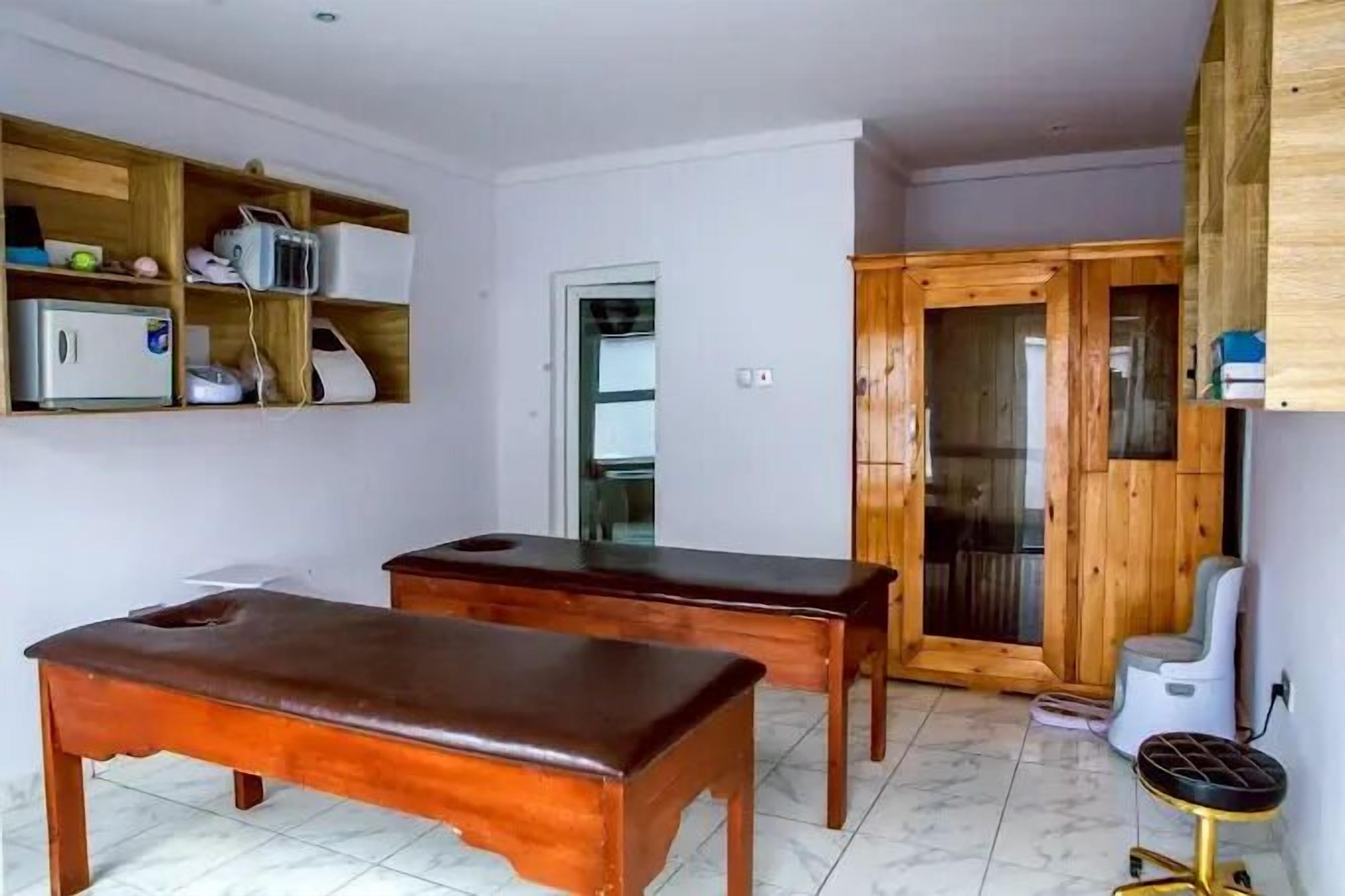 Una habitación con dos mesas de masaje de madera, un armario de madera y un taburete pequeño.