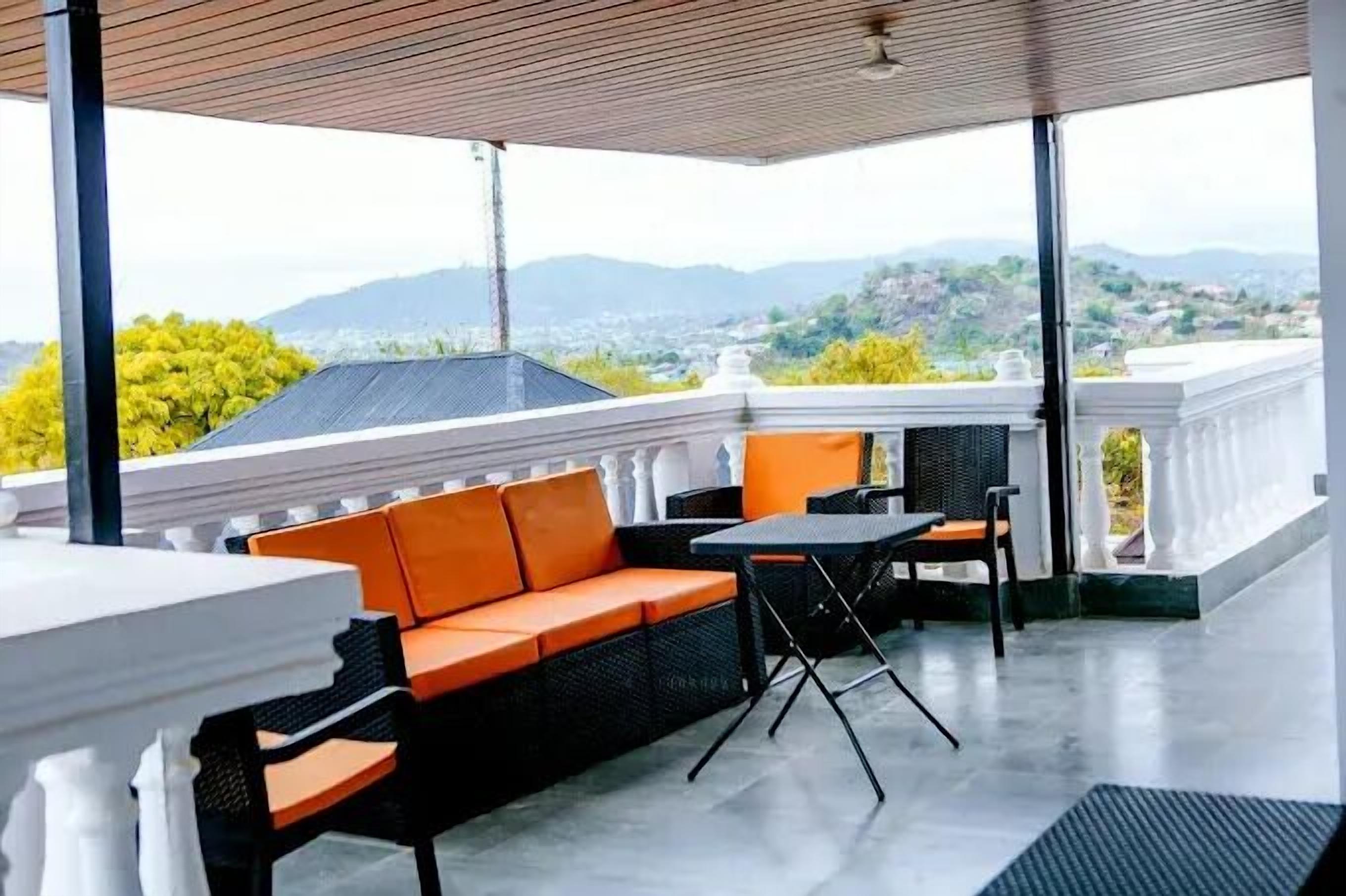 An outdoor seating area with a view of distant hills and a cityscape.