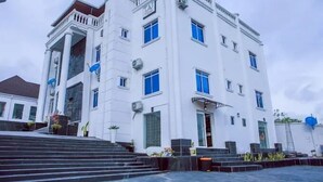 A white building with blue windows and a central entrance. - TAJ SUITES  (Ado Ekiti)