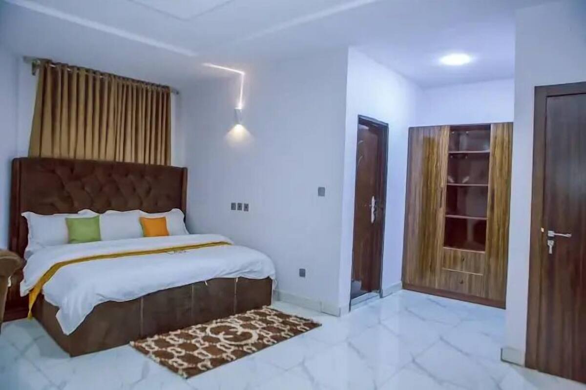 Une chambre à coucher avec un grand lit, une tête de lit, une table de chevet, une commode, un tapis à motifs et une armoire avec un miroir.