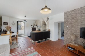 Uma cozinha moderna com bancada preta, luminária pendente e parede de pedra.