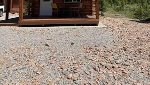 A wooden cabin with a porch, a door, and windows, set against a mountainous backdrop. - Index Peak Cabin (Silver Gate)