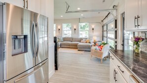 A modern kitchen with stainless steel appliances, a dining area with a dark countertop, and a living room with a sofa and a coffee table. - Waterfront Deck w/ Fire Pit: Lake Spokane Gem! (Nine Mile Falls)