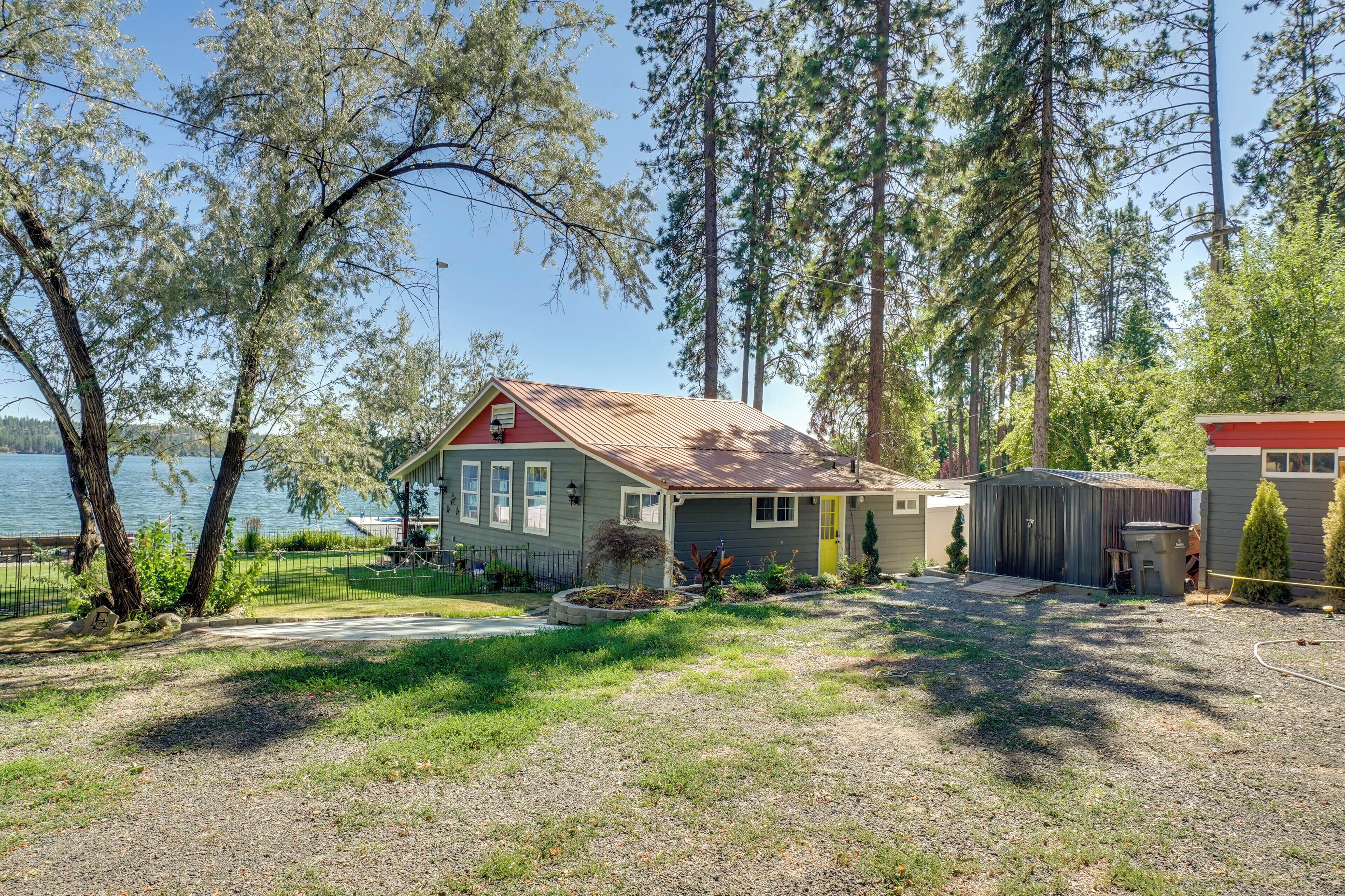 A house with a red roof, a small porch, and a yard with a gravel path.