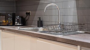 Una cocina moderna con un lavamanos de acero inoxidable, un escurreplatos y una cafetera.
