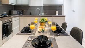 Cocina moderna con una mesa lista para el desayuno, con platos negros, vasos y una pequeña planta en maceta.