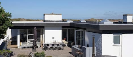 A modern house with a patio area, outdoor seating, and a view of the landscape.