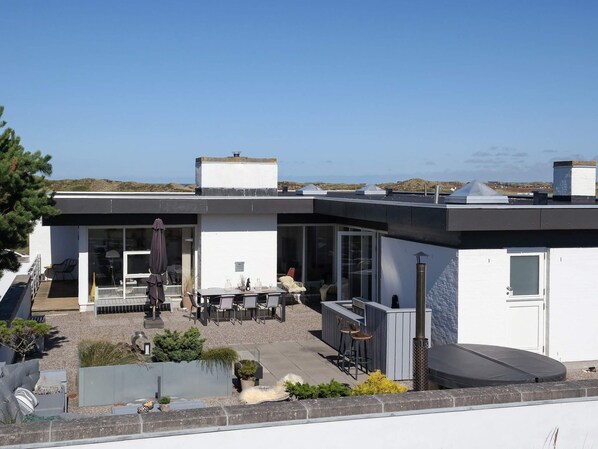 A modern house with a patio area, outdoor seating, and a view of the landscape.