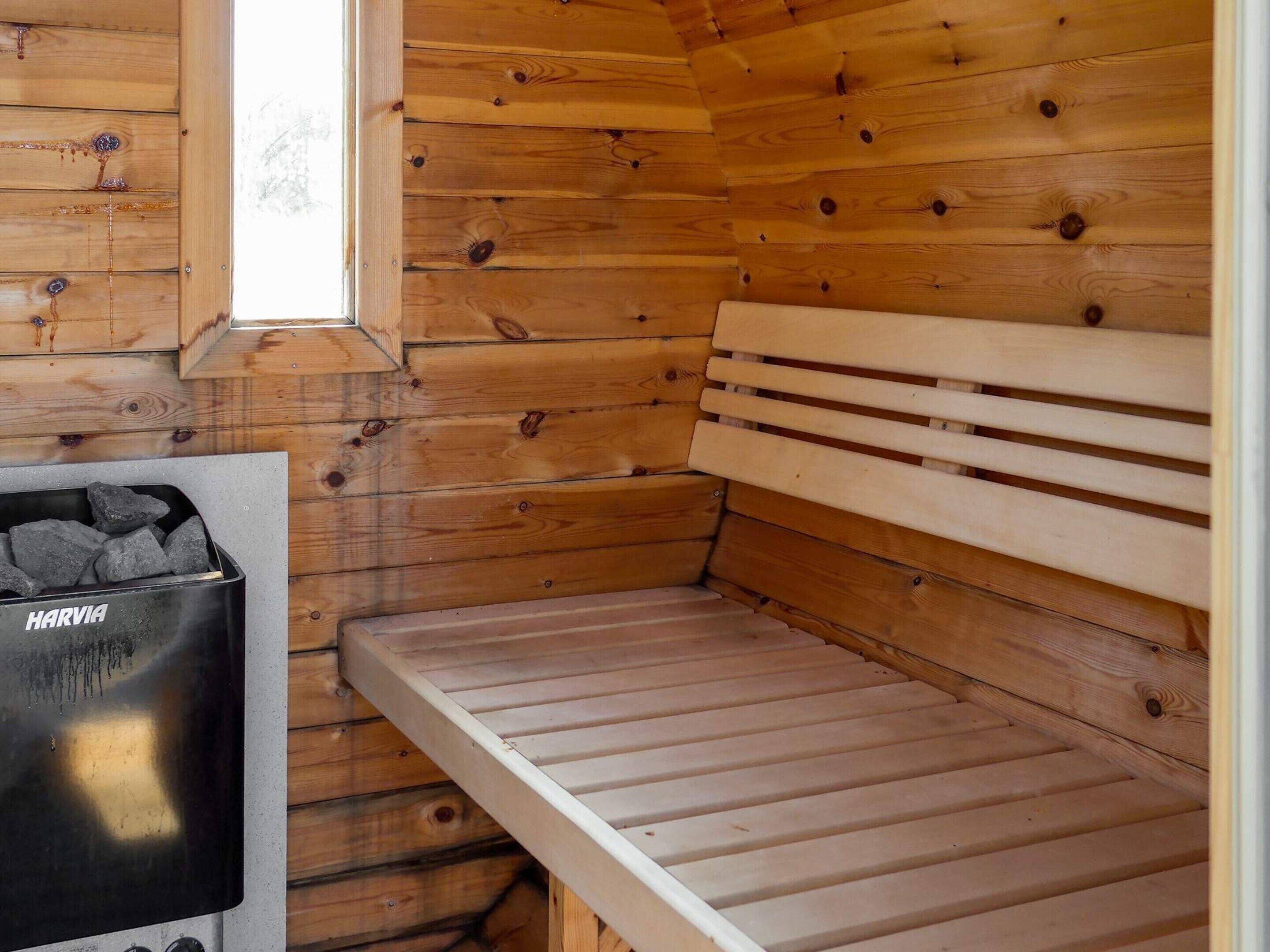 A wooden sauna room with a bench and a Harvia sauna heater.