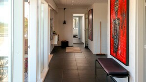 Ein Flur mit einer Bank, Kunstwerken und einer Tür zu einem Zimmer.
